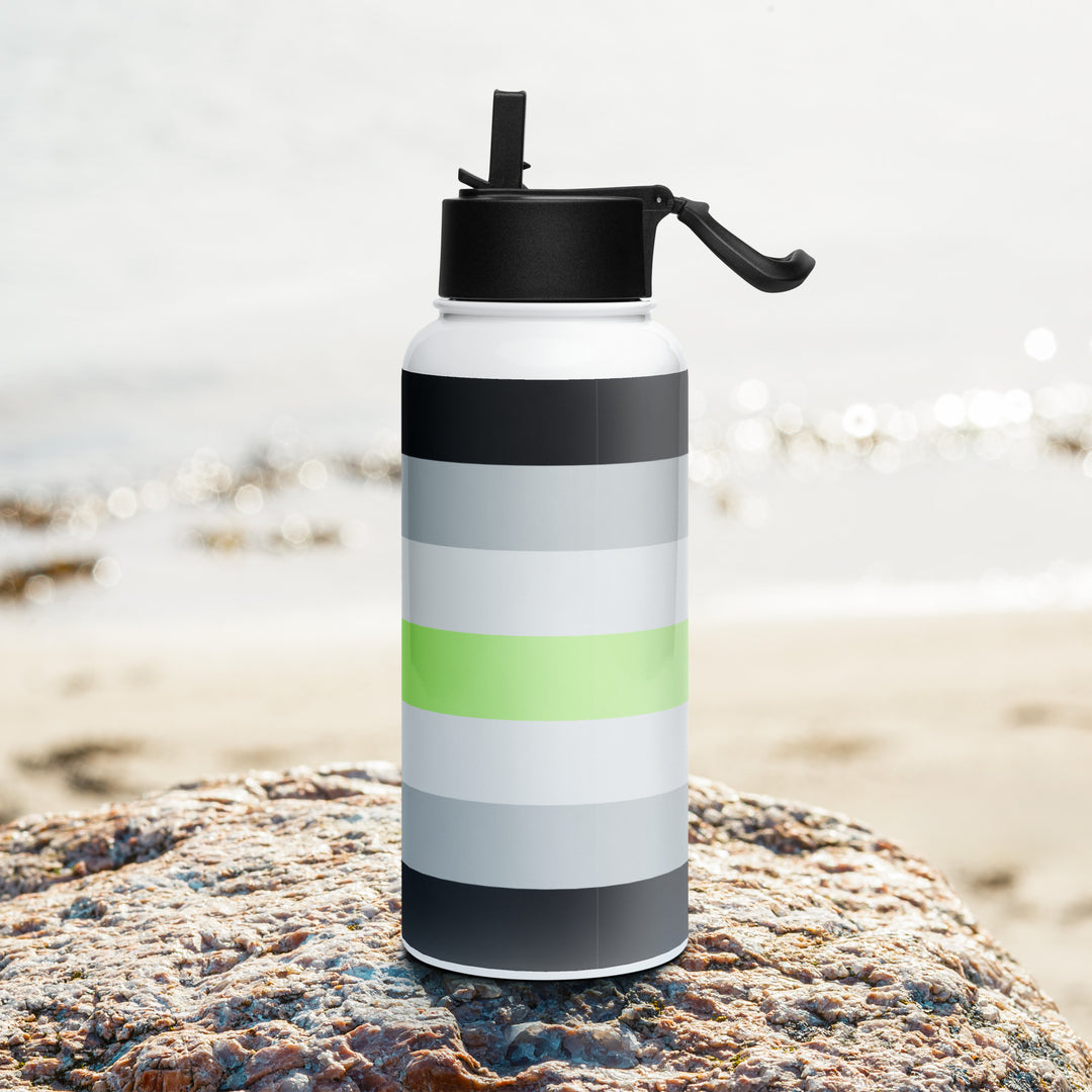 Stainless steel water bottle with a Agender Pride Flag printed around it, on a rock with a beach background. By The Rainbow Stores