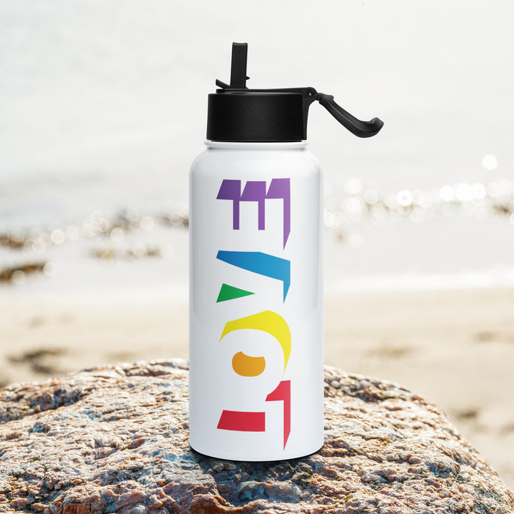 Stainless steel water bottle with athe shadow of the word love on the side, with each shadow in a colour of the Rainbow Pride Flag, on a rock with a beach background. By The Rainbow Stores
