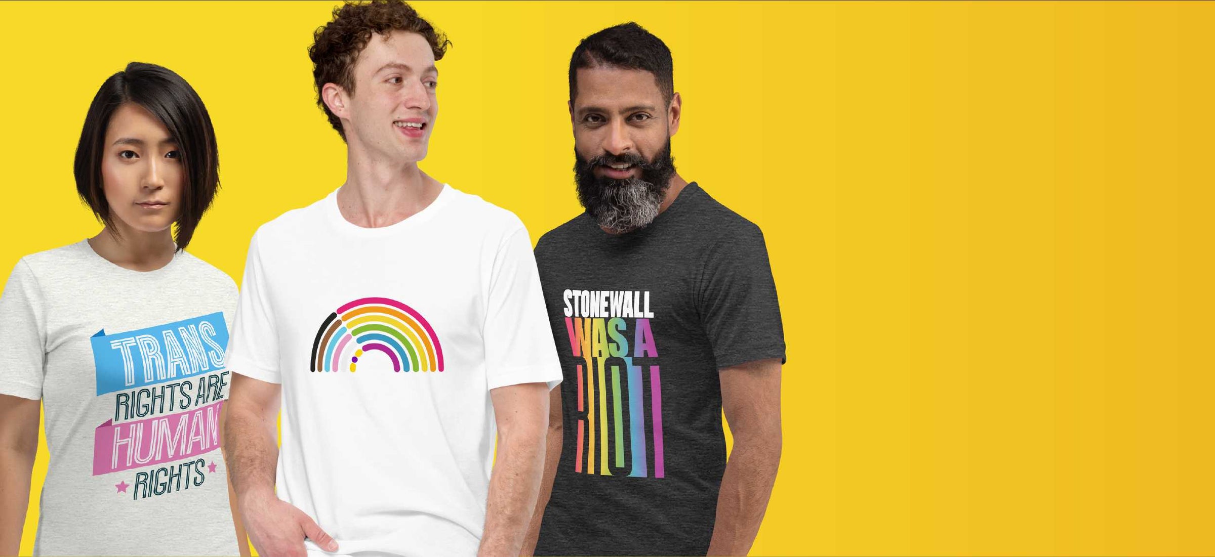 Three people wearing t-shirts with Pride designs and text on a yellow background. The First says Trans Rights are Human Rights The second is a rainbow but in the stripes of the Intersex Inclusive Progress Pride Flag. The third says Stonewall was a riot.