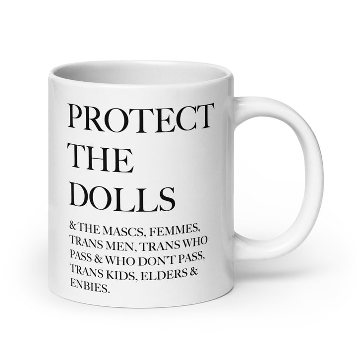 A white ceramic mug with the words Protect The Dolls And The Mascs , femmes, trans men, trans who pass and who don't pass, trans kids, elders and enbies in black.